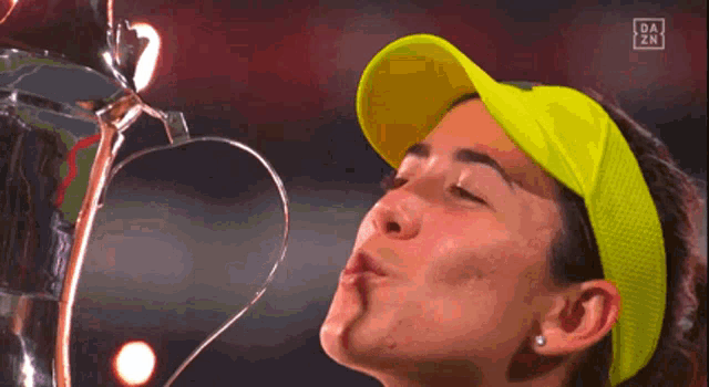 a woman in a yellow hat kisses a trophy with da zn written on the bottom