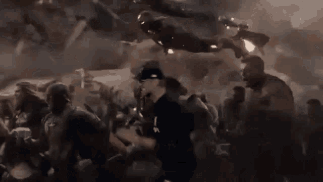 a man is standing in front of a crowd of people while iron man is flying in the air .