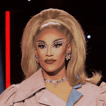a woman with blonde hair wearing a pink jacket and earrings