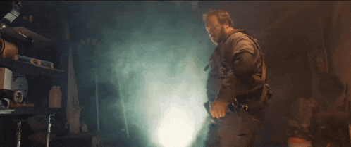 a man is standing in a dark room with a flashlight in his hand