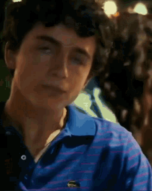 a young man wearing a blue striped shirt with a lacoste logo on it