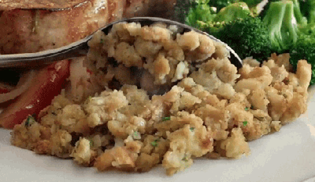 a plate of food with stuffing and broccoli and a spoon