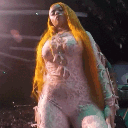 a woman with long blonde hair is standing on a stage in front of a crowd .