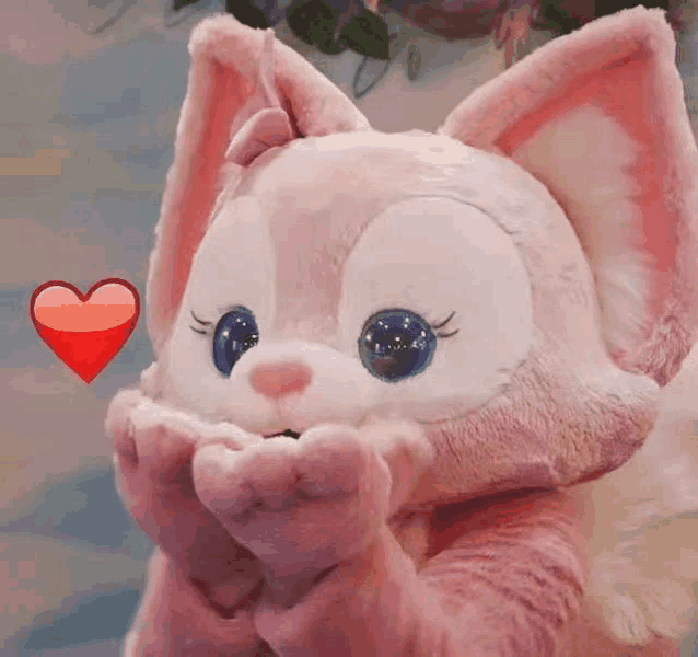 a stuffed animal in a pink and white costume with a red heart behind it .