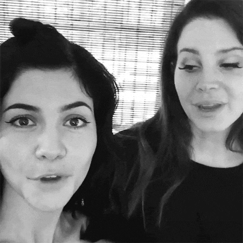 a black and white photo of two women talking