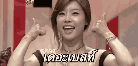 a woman is smiling and giving a thumbs up sign in a foreign language