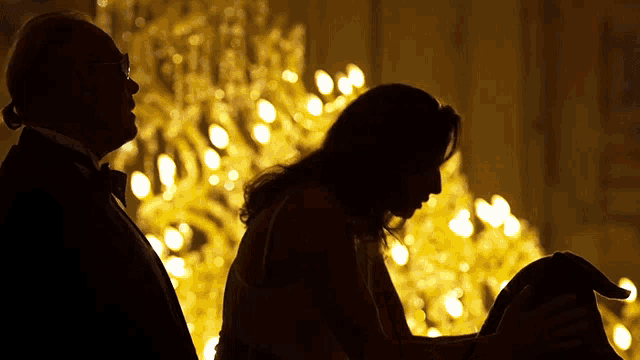 a man and a woman are sitting in front of a chandelier in a dark room