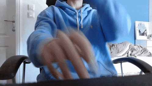a man in a blue hoodie is sitting in a chair