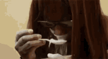 a woman is eating something with a spoon in her mouth .