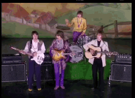 the beatles are playing their guitars and drums on a stage