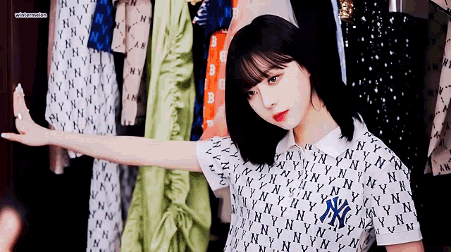a woman wearing a ny shirt is standing in front of a closet full of clothes