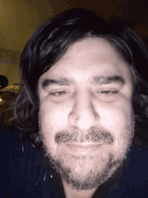 a man with long hair and a beard is smiling