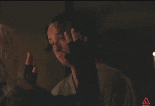 a man in a dark room with a red triangle behind him