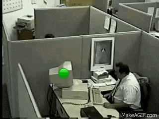 a man is sitting at a desk in front of a computer with a green light on the monitor .