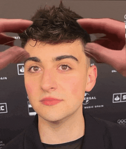 a man 's head is being touched by a person in front of a universal music spain logo