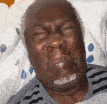 an elderly man is laying in a hospital bed with his eyes closed and a beard .