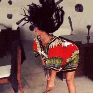 a woman in a red and green dress is standing on her knees with her hair in the air .