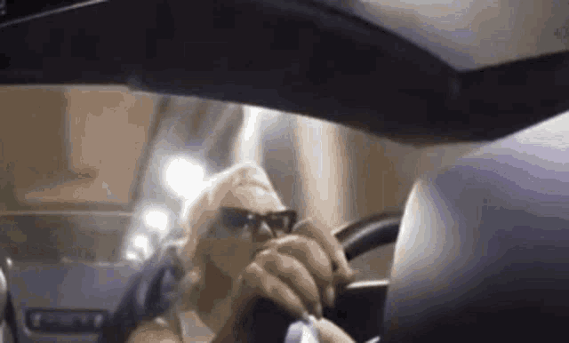 a woman is sitting in the driver 's seat of a car talking on a cell phone .