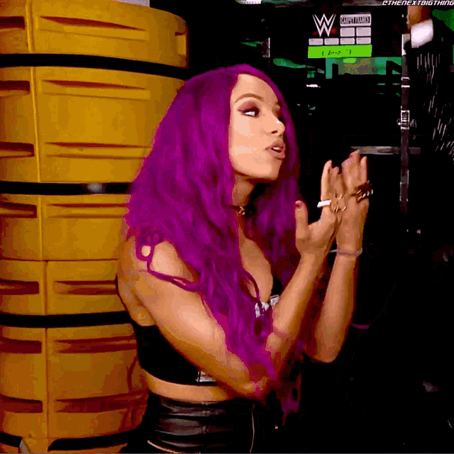 a woman with purple hair stands in front of a sign that says ' wrestling ' on it