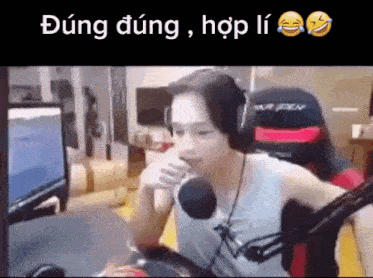a man wearing headphones is sitting in front of a microphone in front of a computer screen .