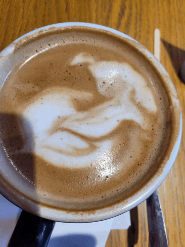 a close up of a cup of cappuccino with a dolphin design on the foam