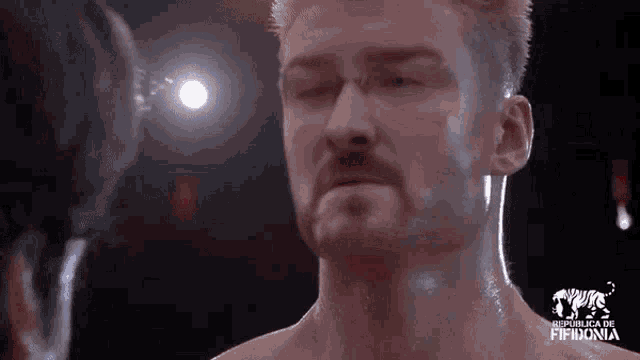 a man with a beard is standing in a boxing ring looking at another man .