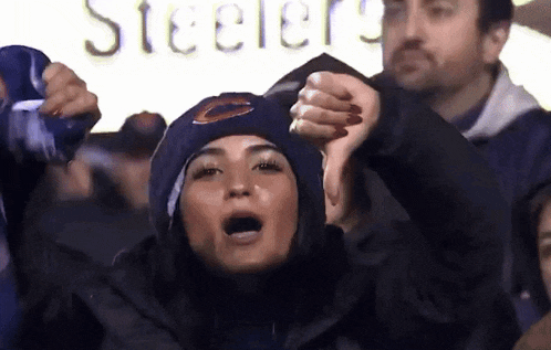 a woman wearing a bears hat is cheering in front of a steelers sign