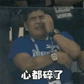 a man in a blue shirt is sitting in a stadium with his eyes closed .