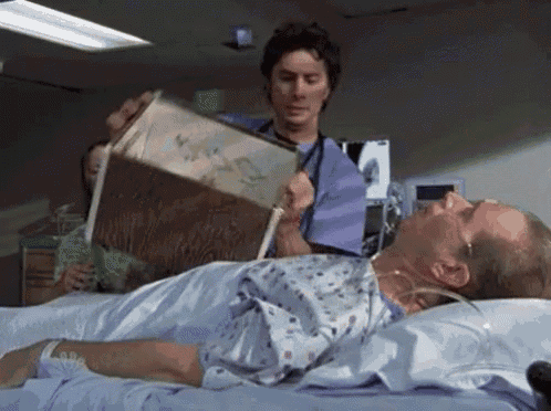 a doctor is reading a book to a patient in a hospital bed .