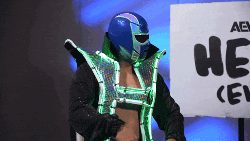 a wrestler stands in front of a sign that says he on it