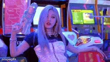 a girl with purple hair is holding a gun in an arcade