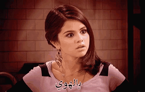 a woman wearing a purple shirt has arabic writing on her chest