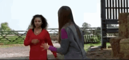 two women are standing next to each other in front of a fence .