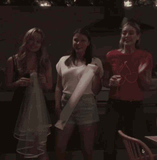 a woman wearing a red shirt with cherries on it is dancing with two other women