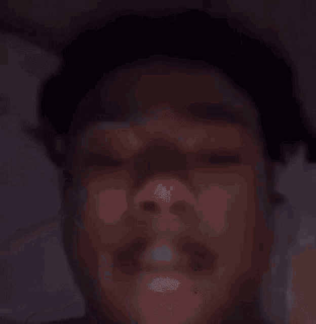 a close up of a person 's face in the dark with a blurry background .