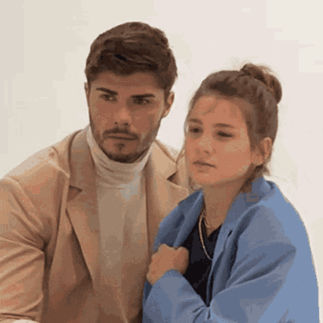 a man and a woman are standing next to each other looking at something