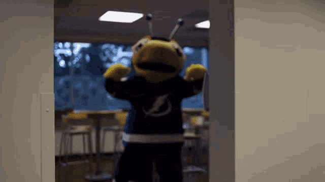 a mascot wearing a lightning shirt is standing in a hallway