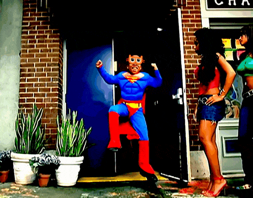 a man in a superman costume is standing in front of a building