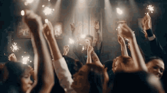 a crowd of people are holding sparklers in their hands .