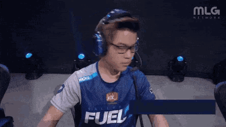 a man wearing headphones and a blue shirt that says fuel on it