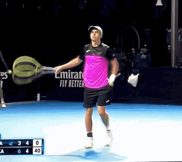 a man in a pink shirt is holding a tennis racquet on a tennis court
