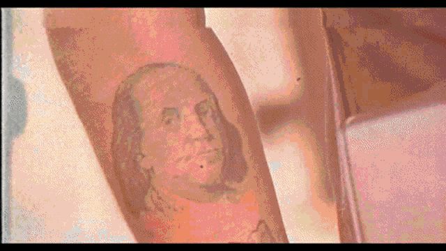 a person has a tattoo of benjamin franklin on their forearm