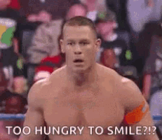 a man without a shirt is standing in a wrestling ring with the words `` too hungry to smile ? ''
