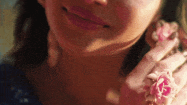 a close up of a woman 's face with a pink flower on her ear