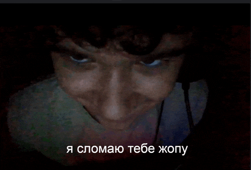 a man 's face is shown in a dark room with the words " я сломаю тебе жопу " in the corner