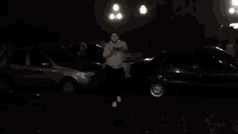 a man in a grey hoodie is dancing in a parking lot .