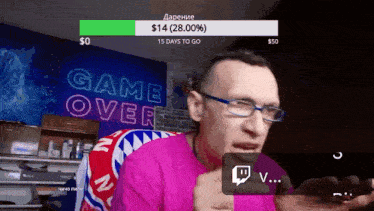 a man wearing glasses stands in front of a neon sign that says game over