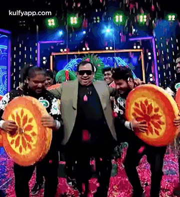 a group of people are dancing on a stage while holding slices of orange .