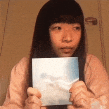 a girl with long hair is holding a picture in her hands .