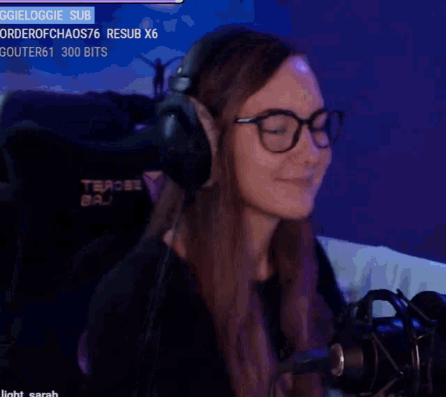 a woman wearing glasses and headphones is smiling in a video